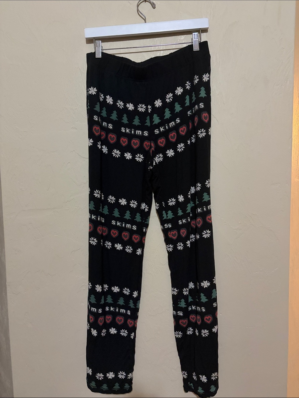 SKIMS Black Holiday PJ pants with Green Trees and Red Hearts.